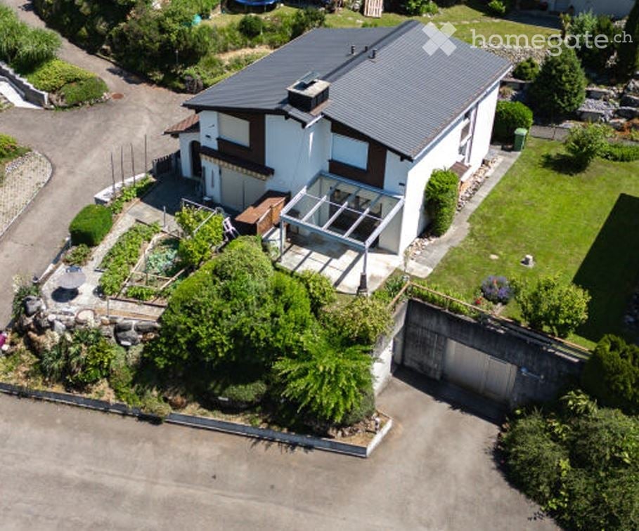 Two-story house with a modern design, featuring a garage, a well-maintained garden, and a covered patio area.