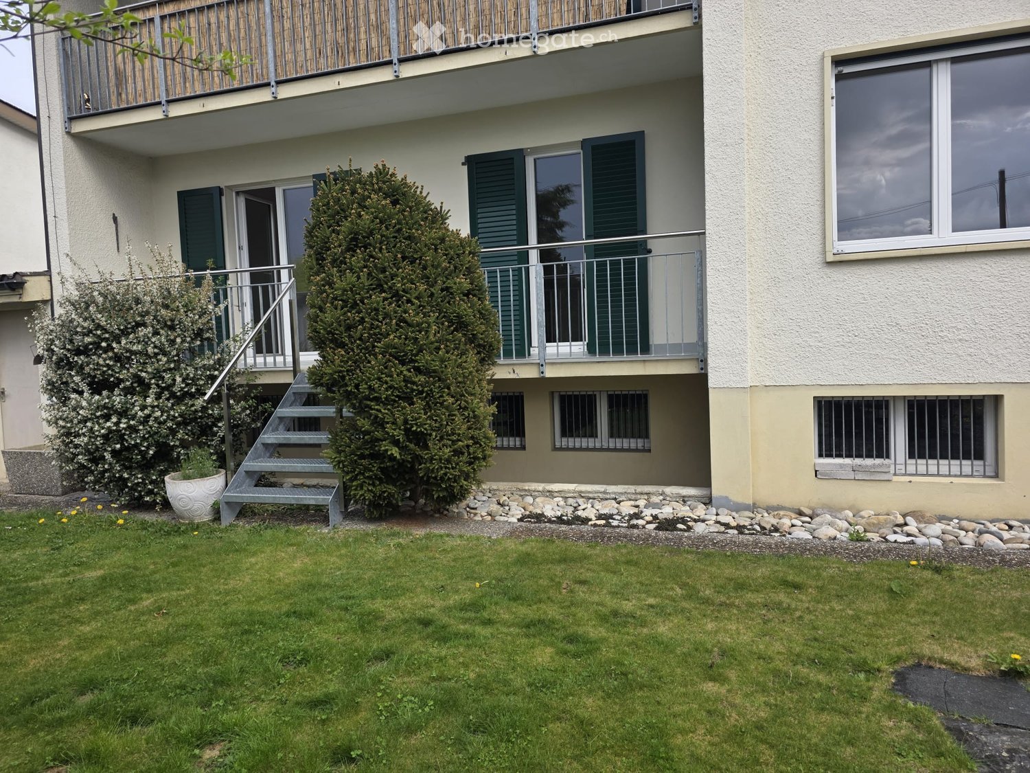 2 story house, white walls, green shutters, balcony, stairs, small garden