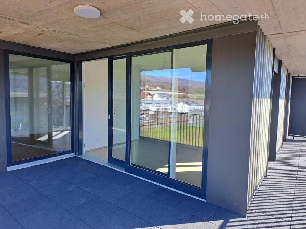 Modern balcony with large glass sliding doors, tiled floor, and a view of the surrounding landscape.