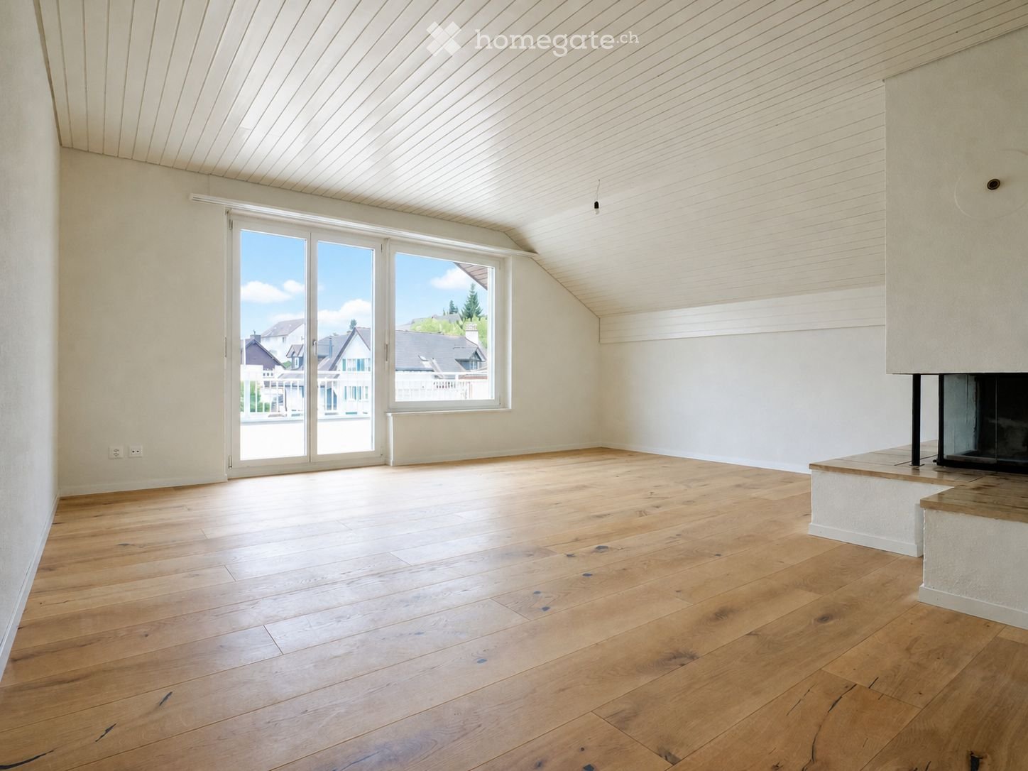 Empty room with wooden flooring, white walls, large sliding glass door, and fireplace.