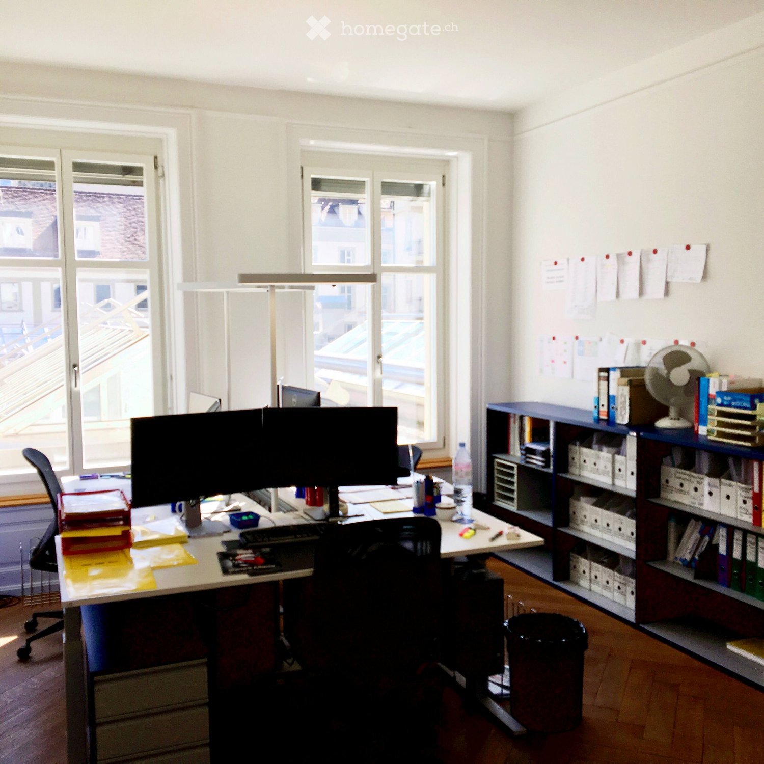 Desk with dual monitors, keyboard, mouse, office chair, shelves, bookshelf, files
