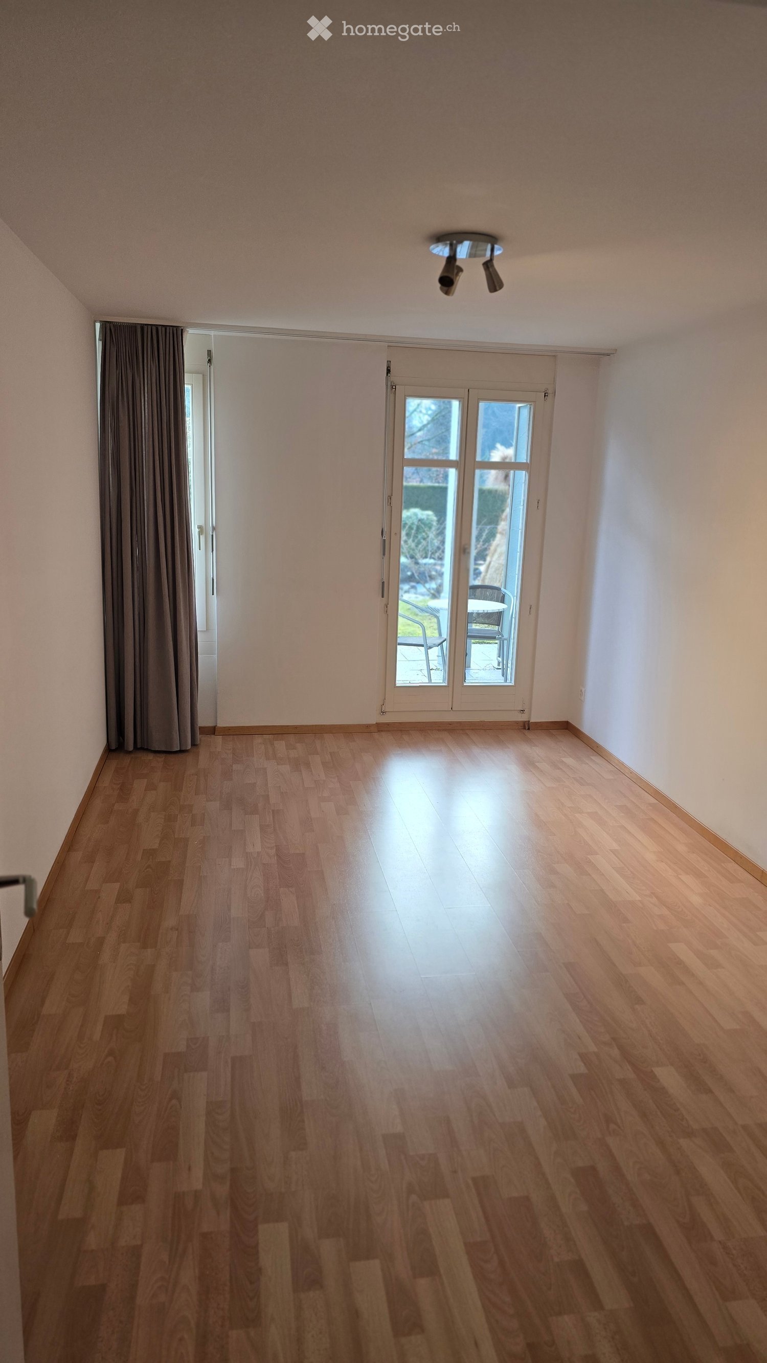 Empty room with wooden flooring, white walls, and a large sliding glass door leading to an outdoor area.