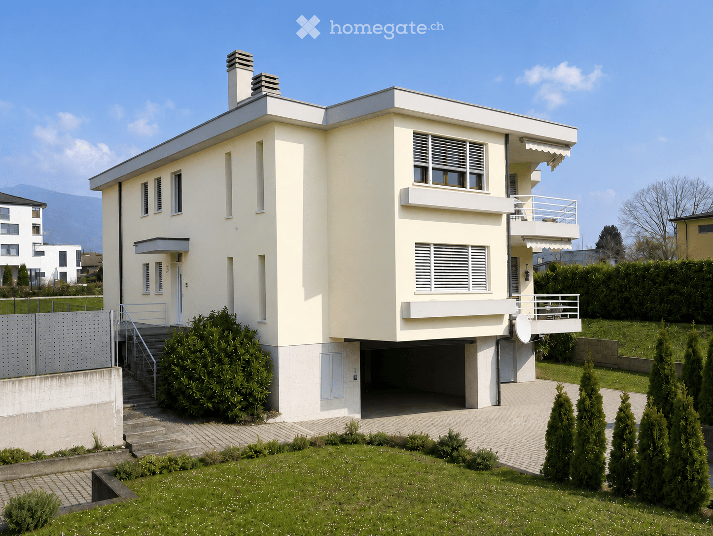 Modern two-story house with white exterior, flat roof, garage, and balcony on the upper level.