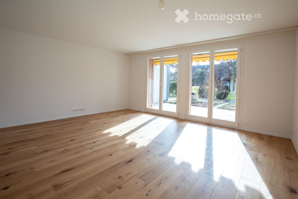 wide room, wood floor, sliding glass doors, balcony, light shining in