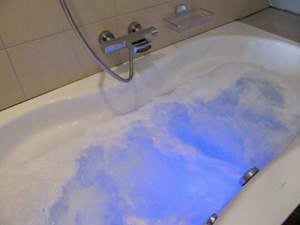 Bathtub with a modern faucet and a sleek design, featuring a blue-tinted water surface.