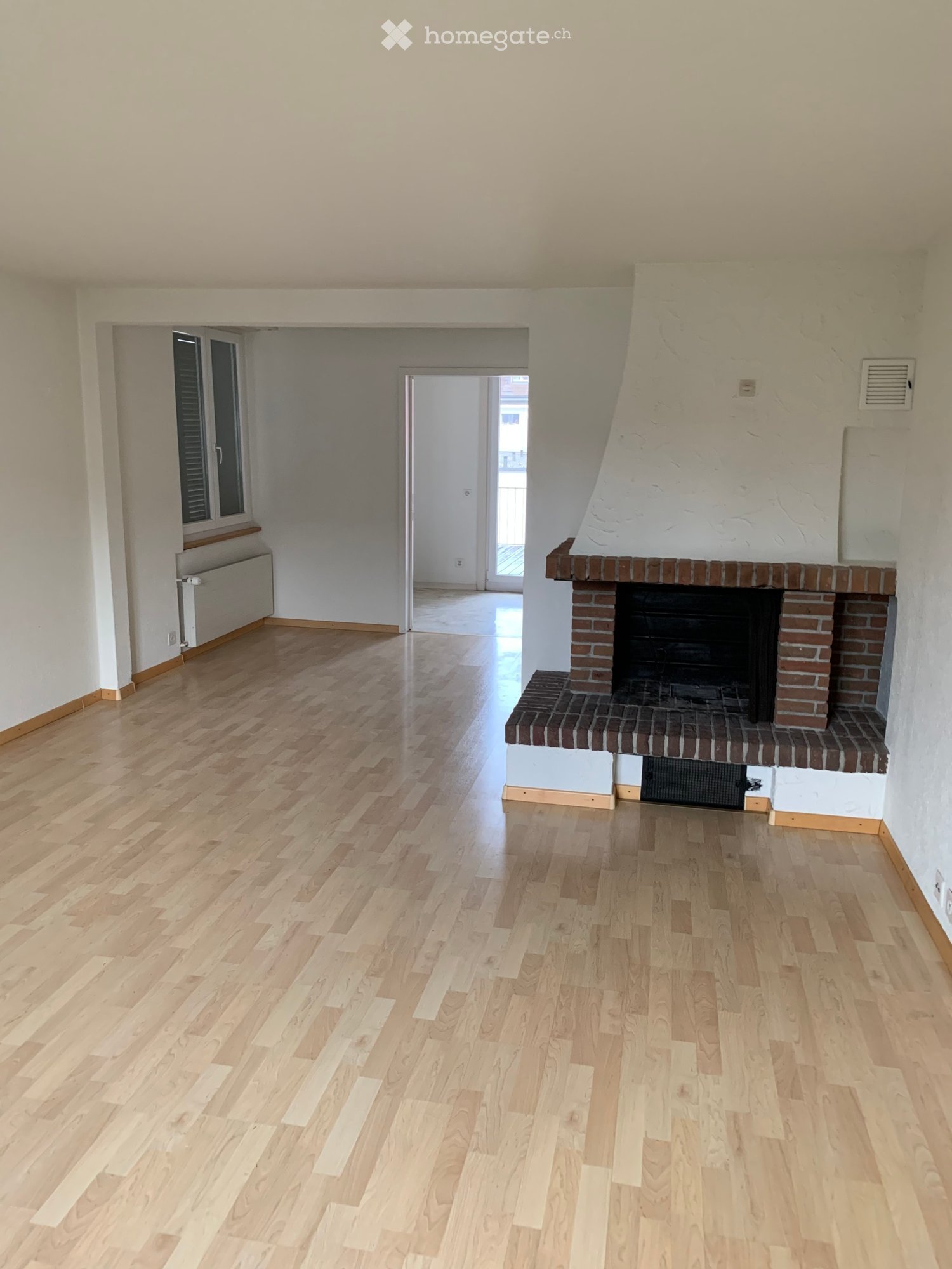 empty room, wooden floor, white walls, fireplace, window, radiator