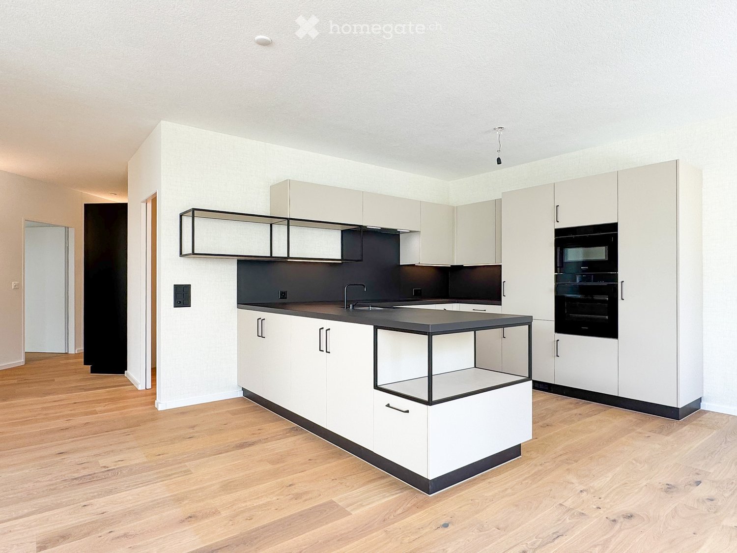 Modern kitchen with white cabinets, black countertop, and integrated appliances including a sink and oven.