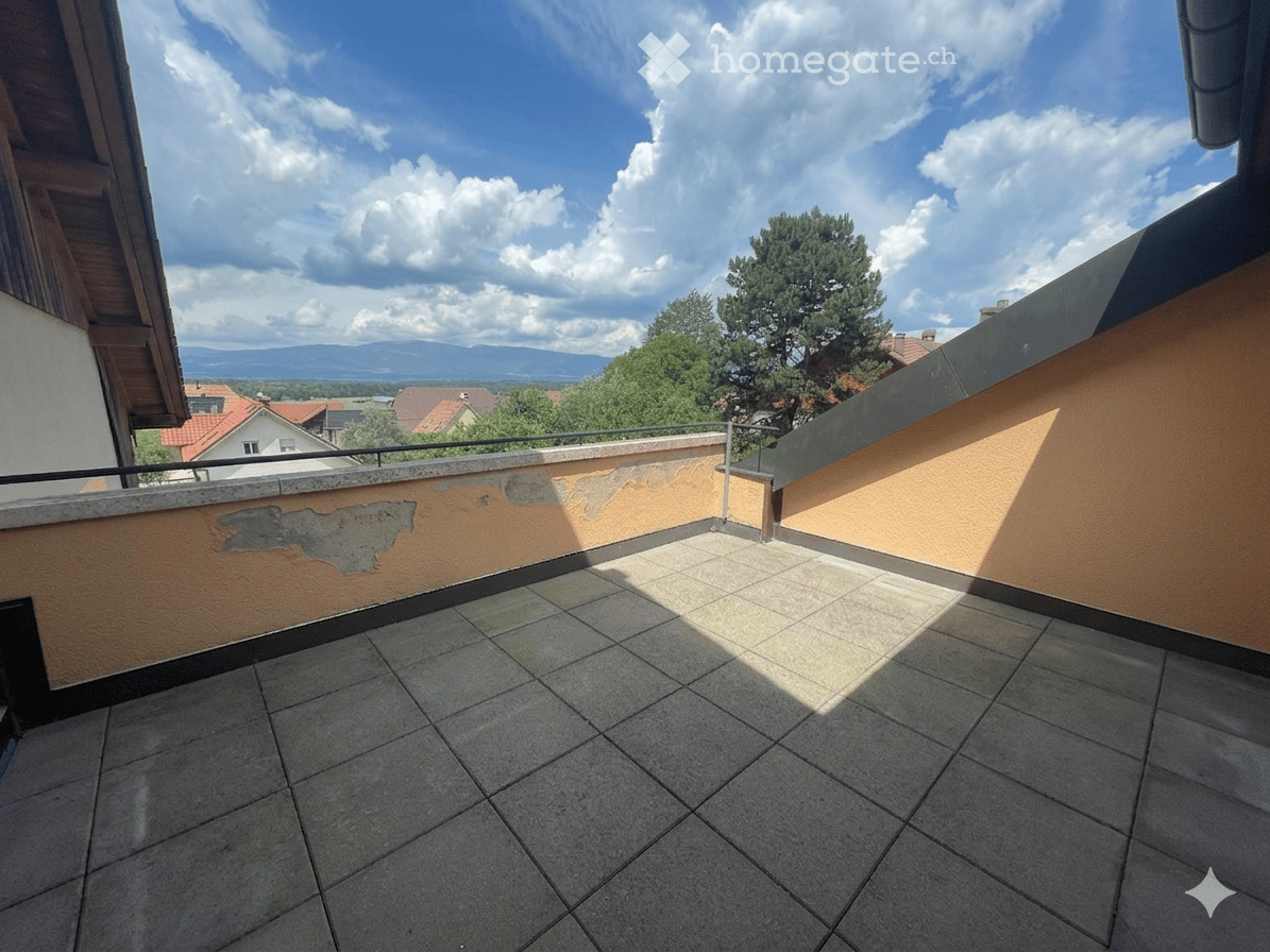 Balcony with tiled floor, low wall, and scenic view of trees and mountains.
