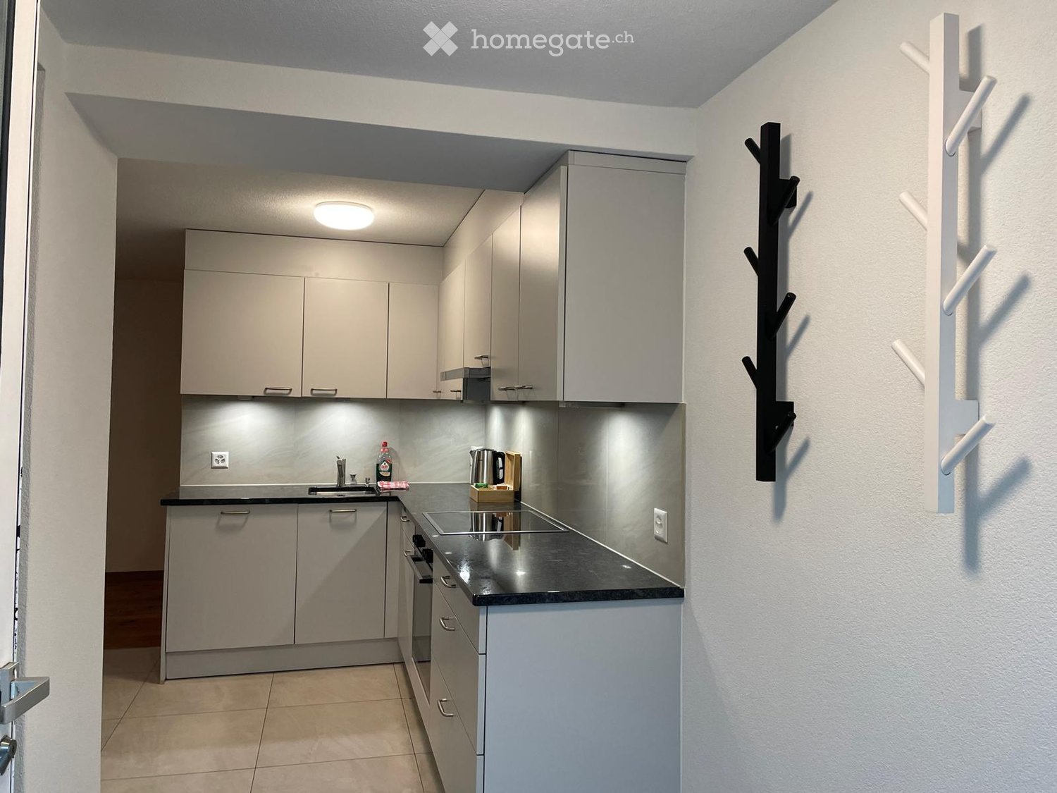 Modern kitchen with white cabinets, stainless steel countertop, sink, and small appliances.