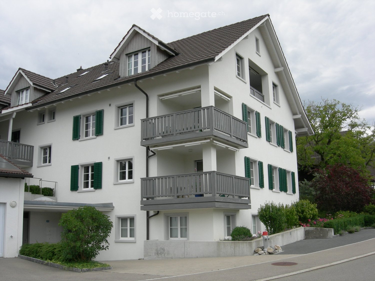 3 story house, white paint, grey roof, multiple balconies, concrete ground floor