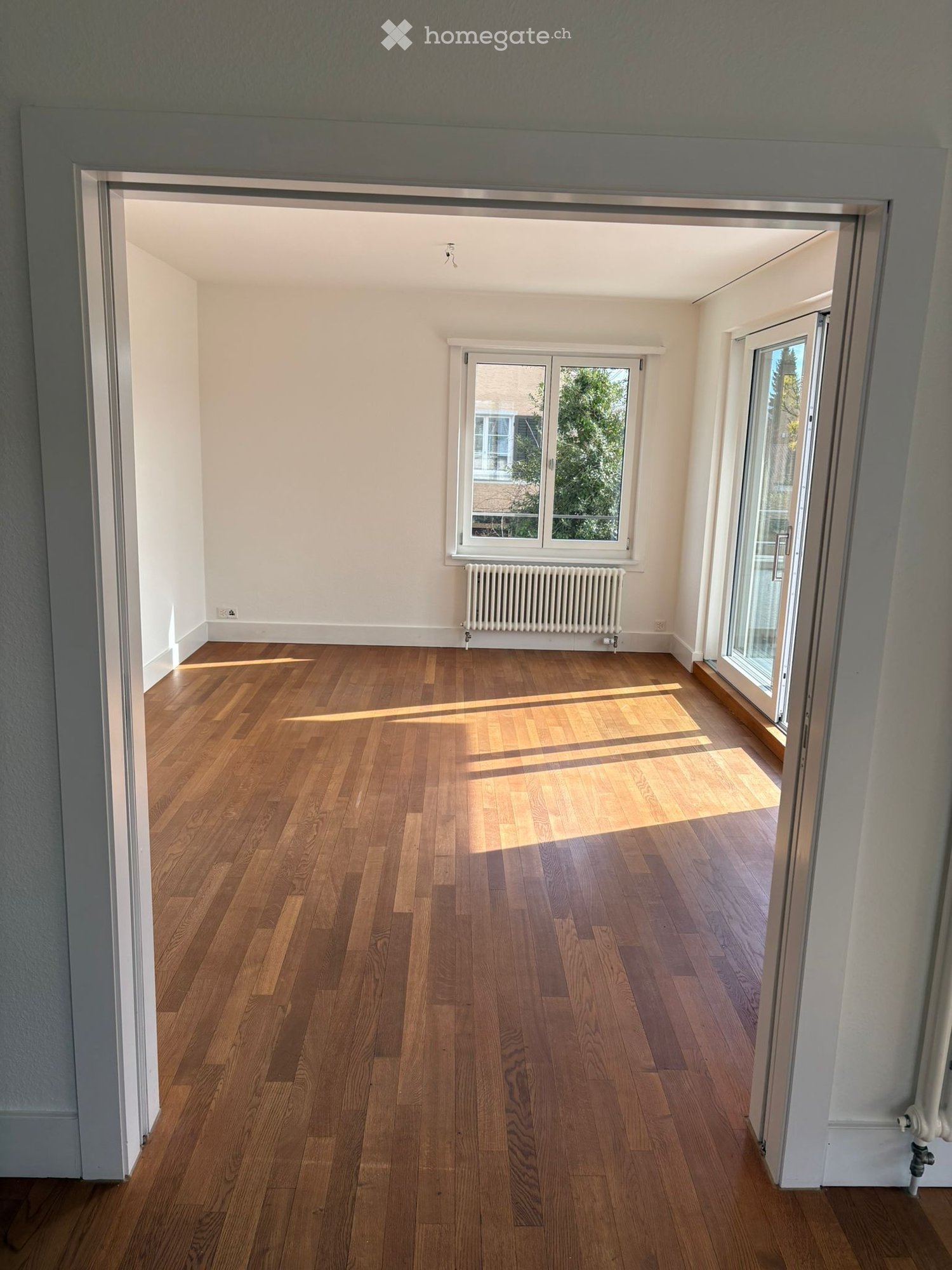 empty room, wooden floor, white walls, windows, radiator, sliding glass door