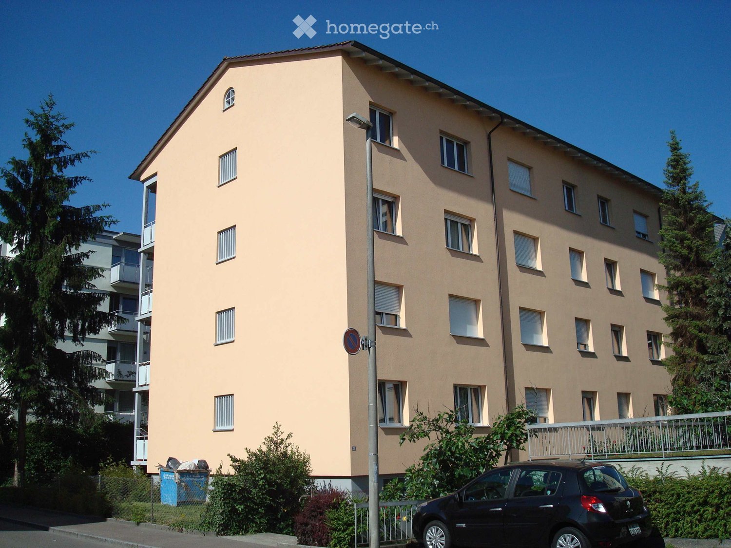 A 4 story beige apartment building with windows and balconies.