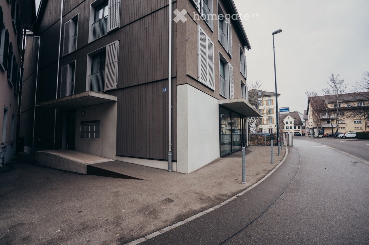 Contemporary multistory residential building, raised ground floor, modern design, windows with shutters, entrance ramp