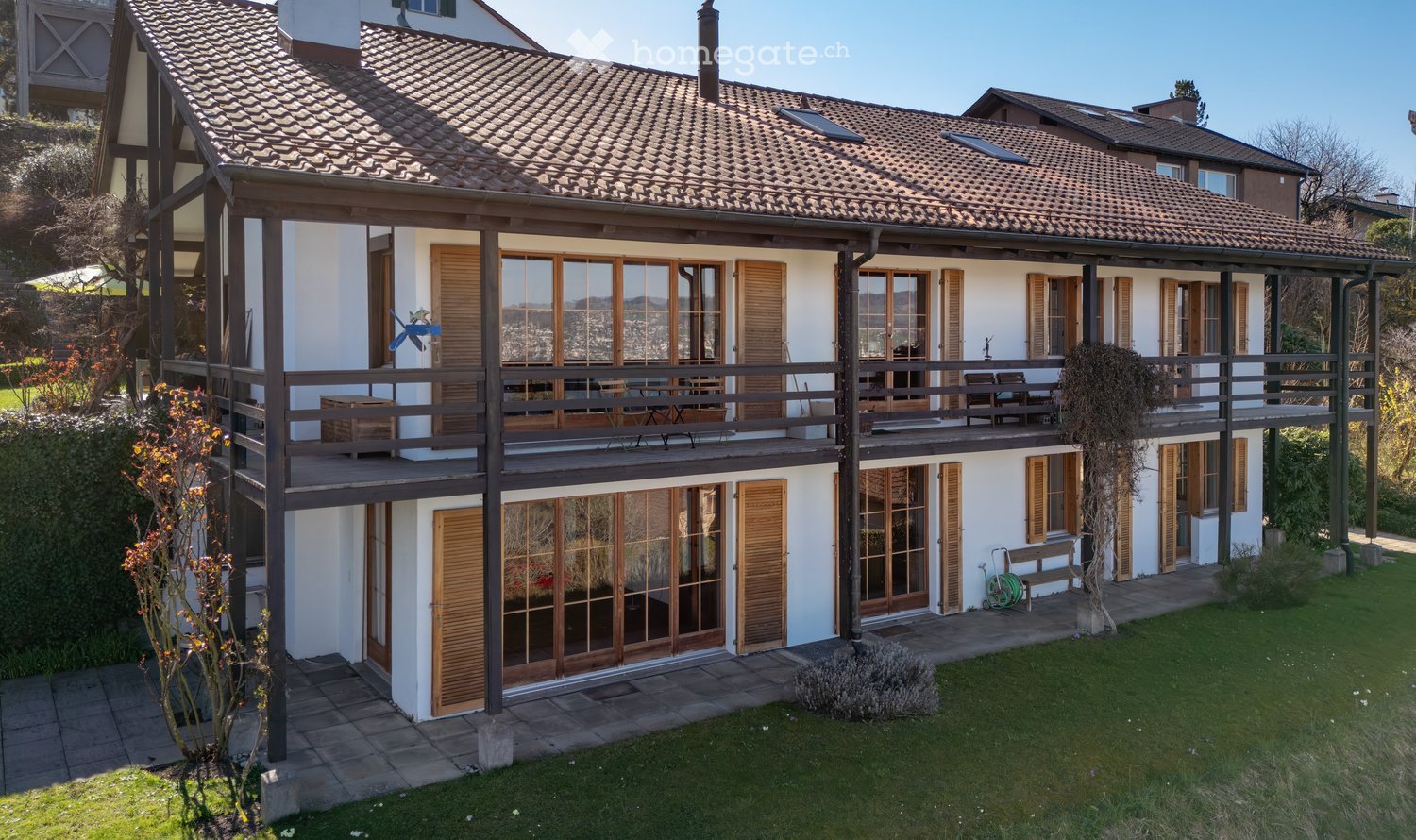 2 story house, brown roof, white walls, large windows, balcony, wooden shutters