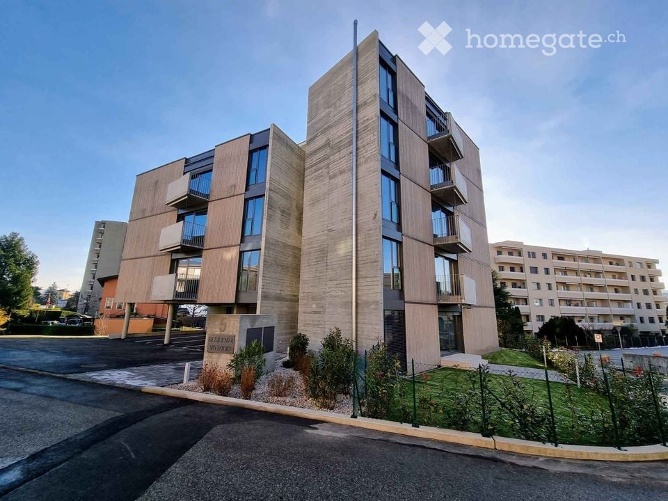 Modern multi-story residential building with balconies, large windows, and a contemporary design.