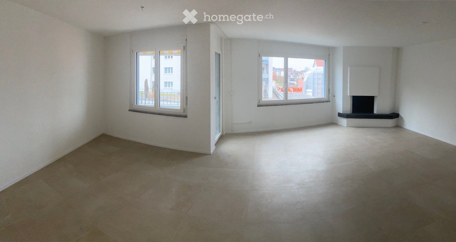 Empty room with white walls, tiled floor, large windows, and a built-in fireplace.