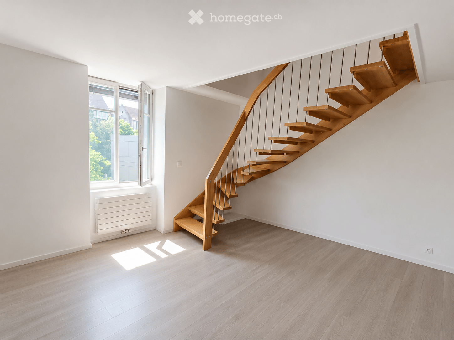 Modern hallway with wooden staircase, light-colored wooden flooring, white walls, and large windows allowing natural light.