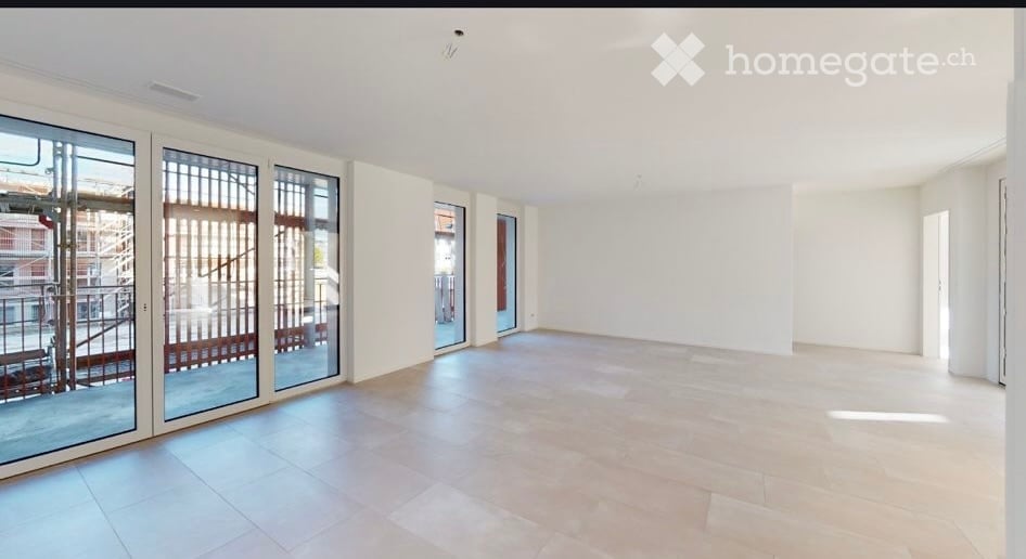 Empty room with large glass sliding doors leading to a balcony, white walls, and tiled floor.