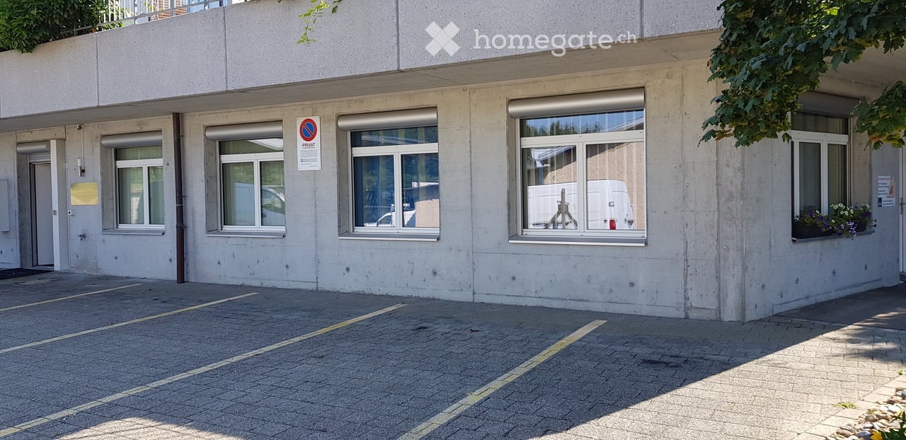 3 story building, concrete facade, 4 windows, sign, flowers in the window sill