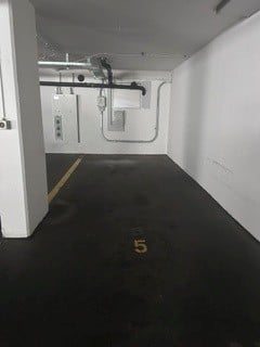 {"type": "Garage", "objects": [], "description": "Empty underground parking space with white walls, exposed pipes, and a marked parking spot labeled \"5\".", "localized_descriptions": {"EN": "Empty underground parking space with white walls, exposed pipes