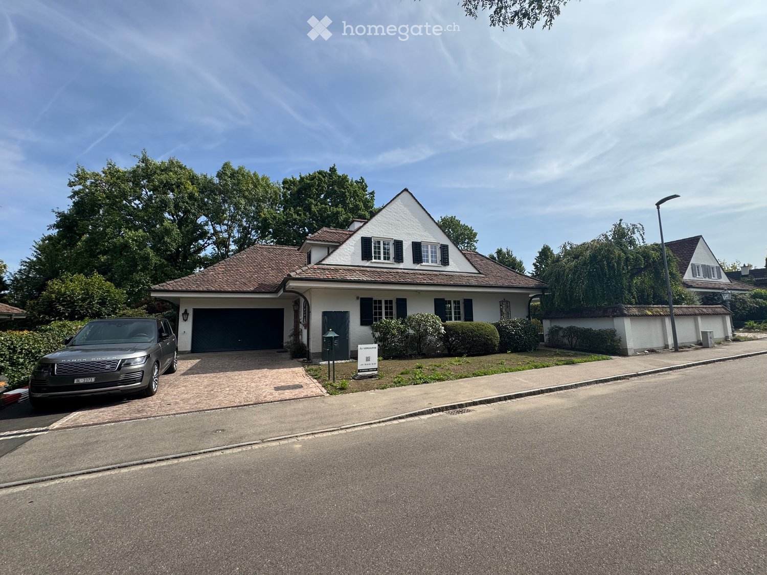 Two-story house with white exterior, dark garage door, and a parked SUV in the driveway.