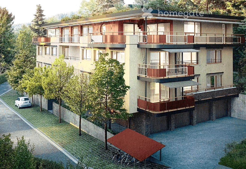 Modern multi-story building with balconies, large windows, and a garage. Surrounded by trees and a parking area.