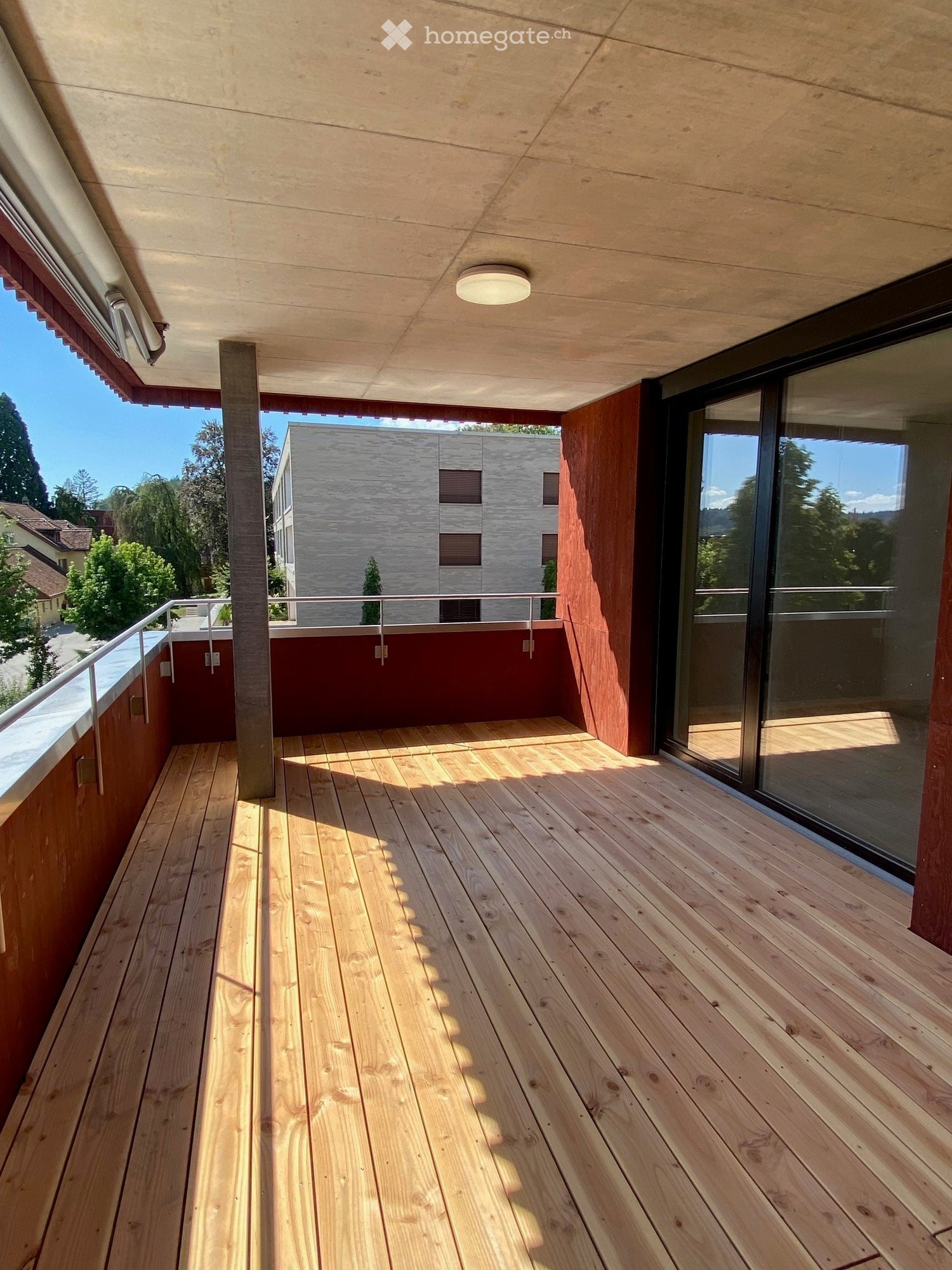 wooden floor, metal railing, glass door, metal ceiling light, view of trees and buildings
