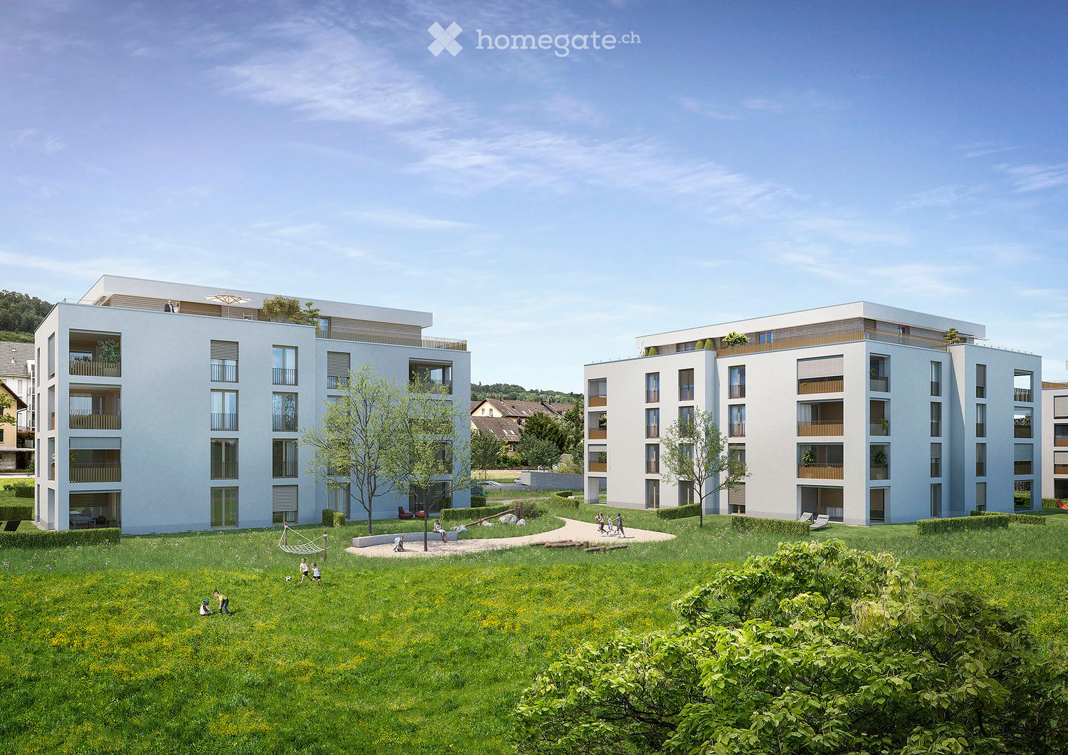 Modern residential complex with multiple apartment buildings, balconies, and a spacious green lawn area with children playing.