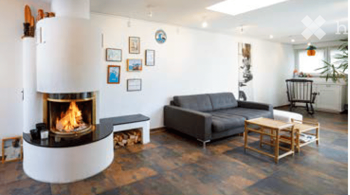 Modern living room with a grey sectional sofa, a white fireplace, a small coffee table, and several picture frames on the wall.