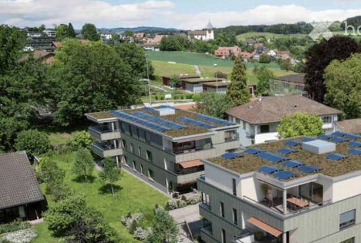Aerial view of a multi-story building with solar panels on the roof and balconies