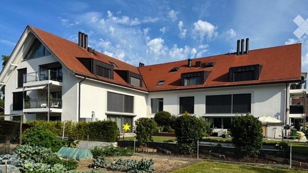 Modern two-story house with white exterior, red-tiled roof, multiple balconies, and well-maintained garden area.