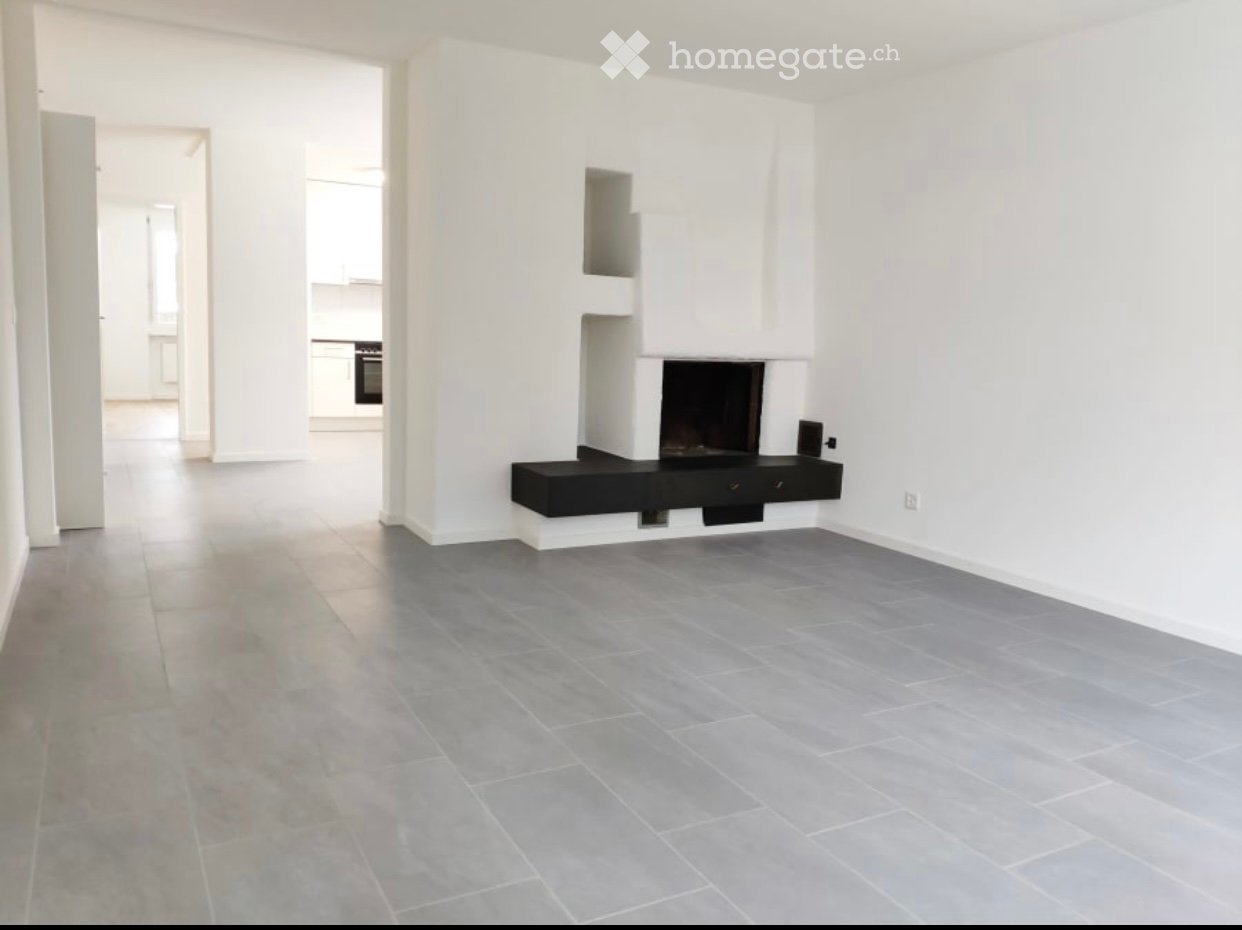 Empty living room with grey tiled floor, white walls, and a built-in fireplace with a black surround.