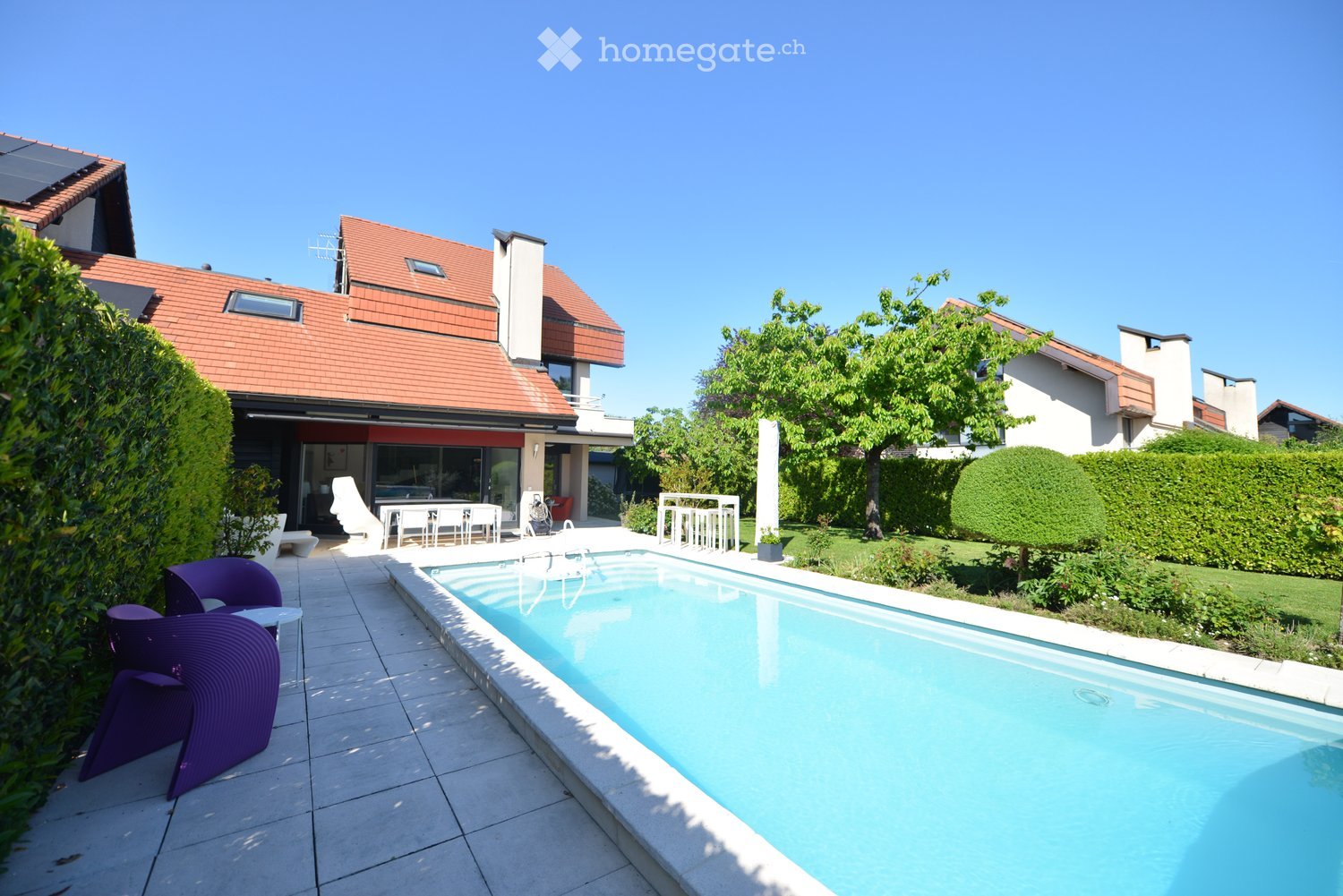 Outdoor area with a swimming pool, patio furniture, and greenery.
