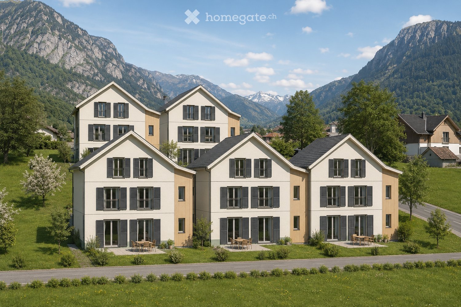 A row of modern, two-story houses with white and beige facades, black shutters, and large windows, set in a green landscape with mountains in the background.