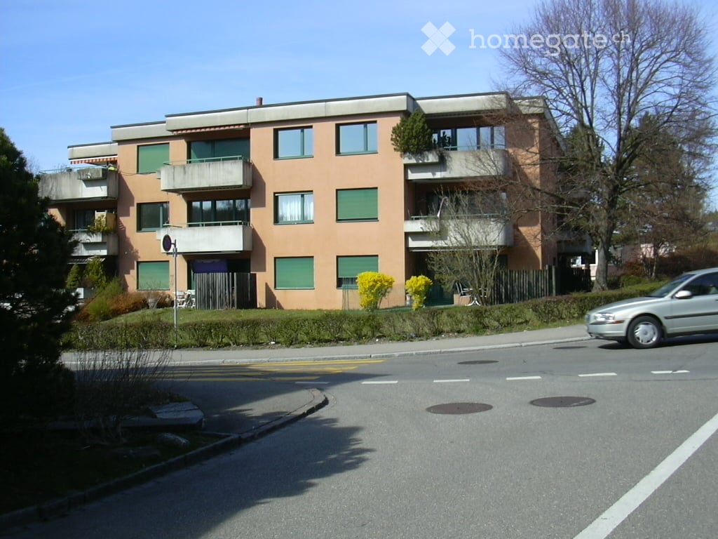 Building. Multi-story residential building with balconies, green shutters, and a landscaped front yard.