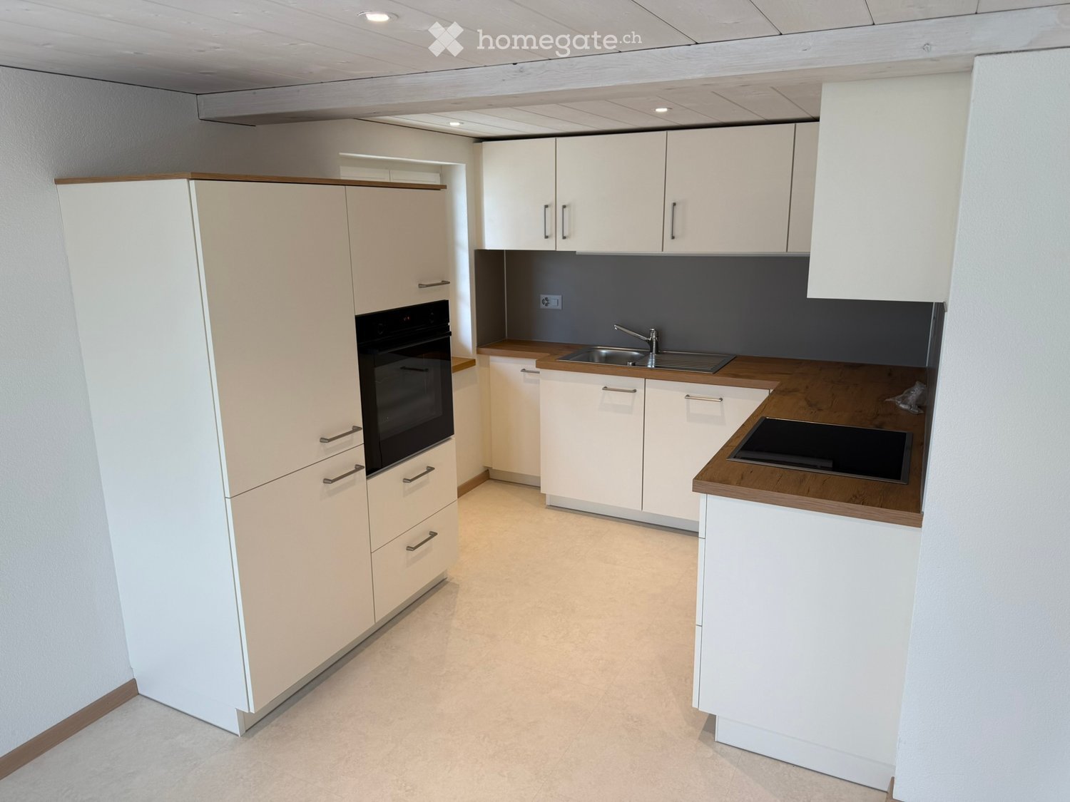 Modern kitchen with white cabinets, wooden countertops, stainless steel sink, and built-in oven.