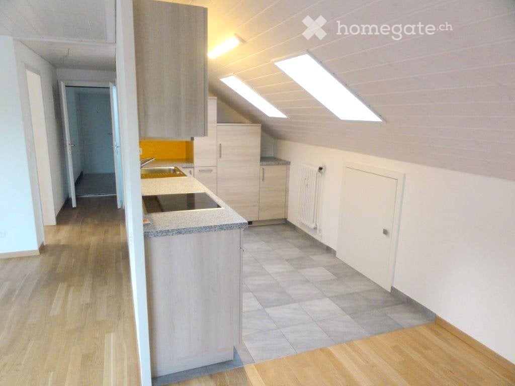 Modern kitchen with light wood cabinets, granite countertop, stainless steel sink, and stove. Skylight windows provide natural light. Wooden flooring throughout.