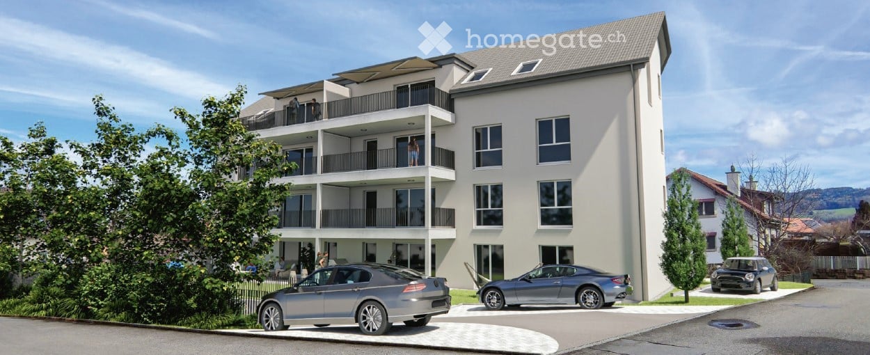 Modern multi-story residential building with balconies, large windows, and a parking area with several cars.