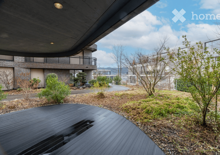 Modern outdoor area with a wooden deck, small garden beds, and a contemporary building in the background.