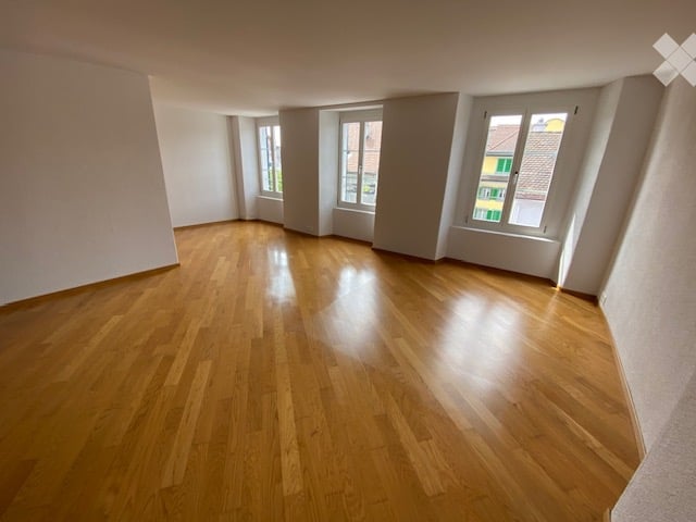 Empty room with wooden flooring and large windows, no furniture or equipment.