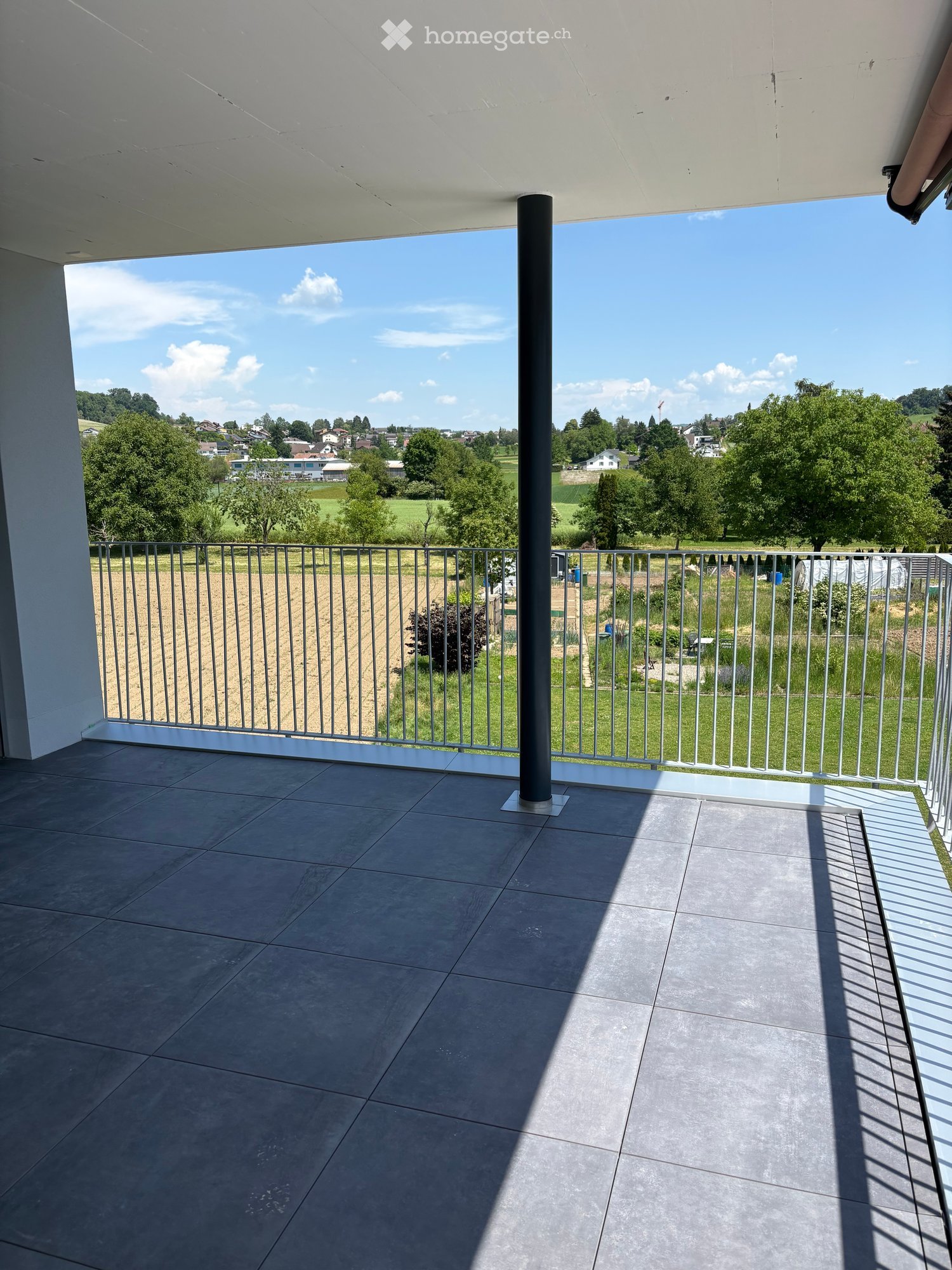 Balcony with tiled floor, metal railing, and scenic countryside view.