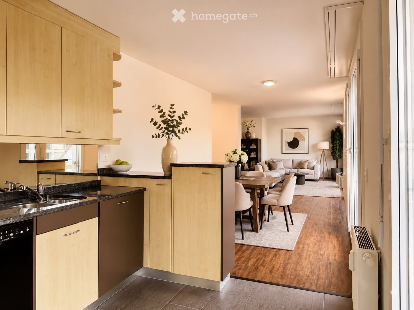 Open-plan kitchen and living area with light wood cabinets, granite countertops, a modern sink, a dishwasher, a white sofa, a coffee table, dining chairs, a dining table, decorative vases, and a potted plant.