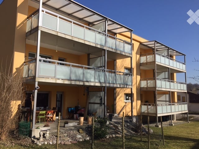 Multi-story residential building with yellow facade, multiple balconies, and outdoor seating area.