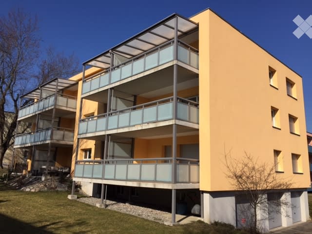 Modern multi-story apartment building with multiple balconies, yellow exterior, modern design.