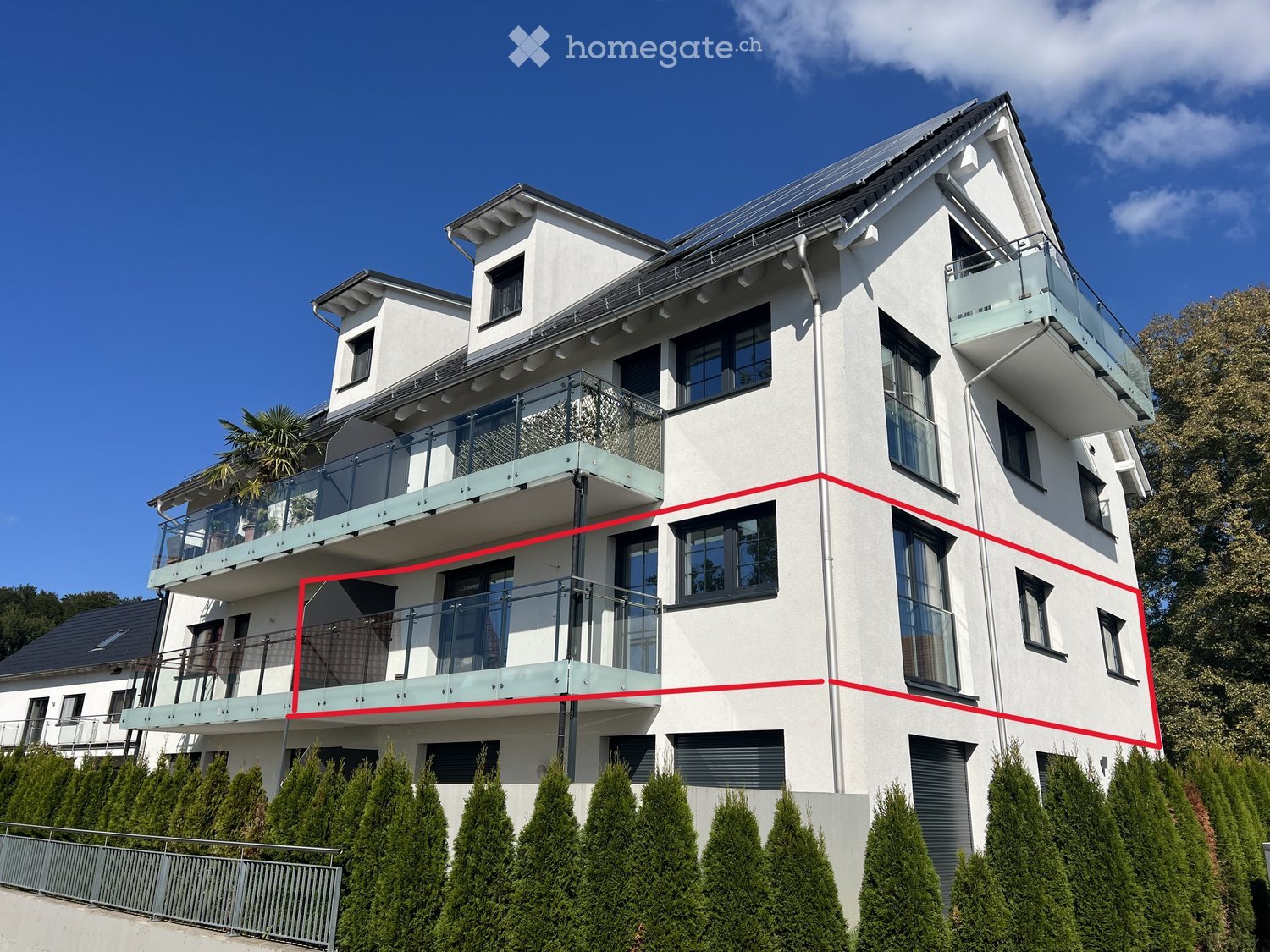 Modern two-story house with white exterior, multiple large windows, and glass balconies.
