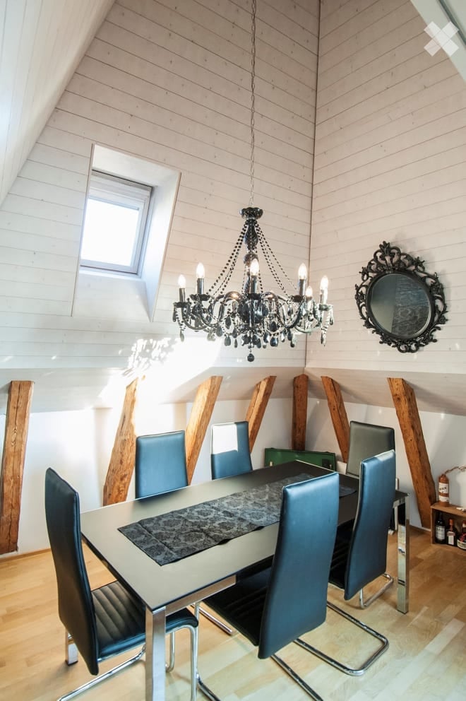 Dining room with a modern glass table, blue chairs, chandelier, and a decorative mirror on the wall.