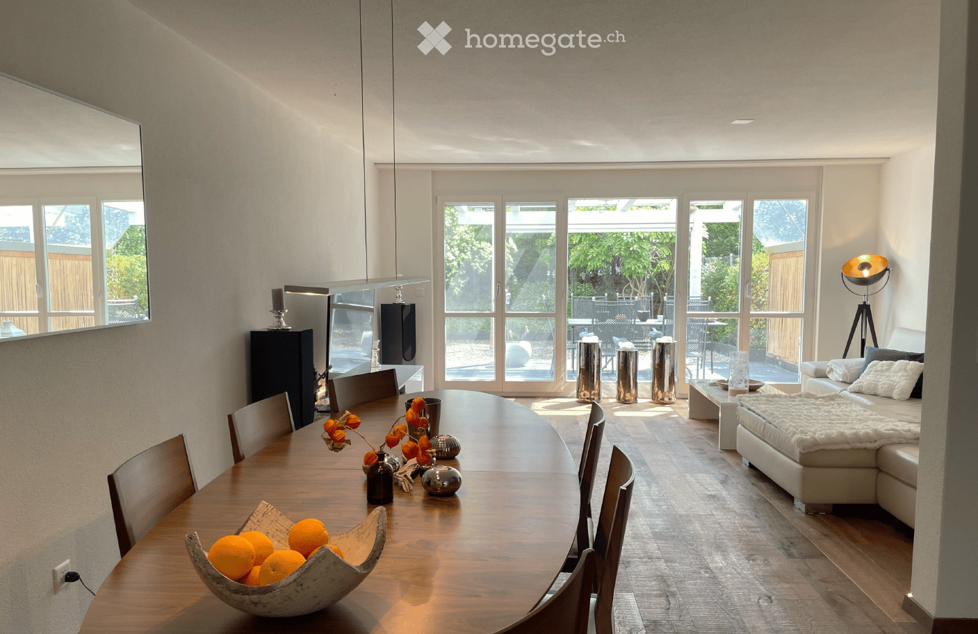 Open-plan living and dining area with large windows, modern furniture, and a view of the garden.