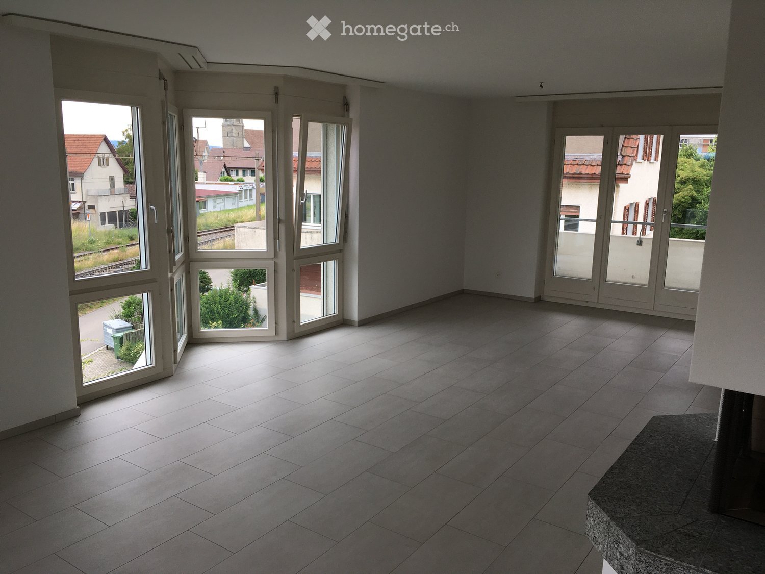 Empty room with large windows and tiled floor, no furniture or equipment.