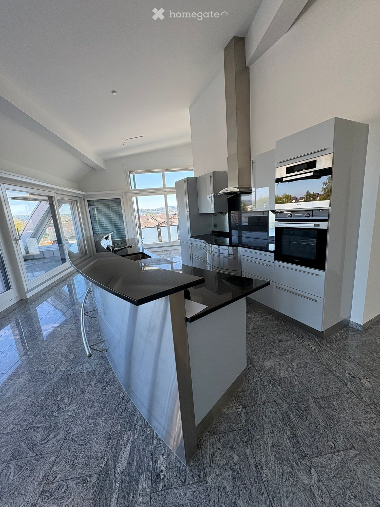 modern kitchen, island with black granite countertop, stainless steel appliances, white cabinets, large windows