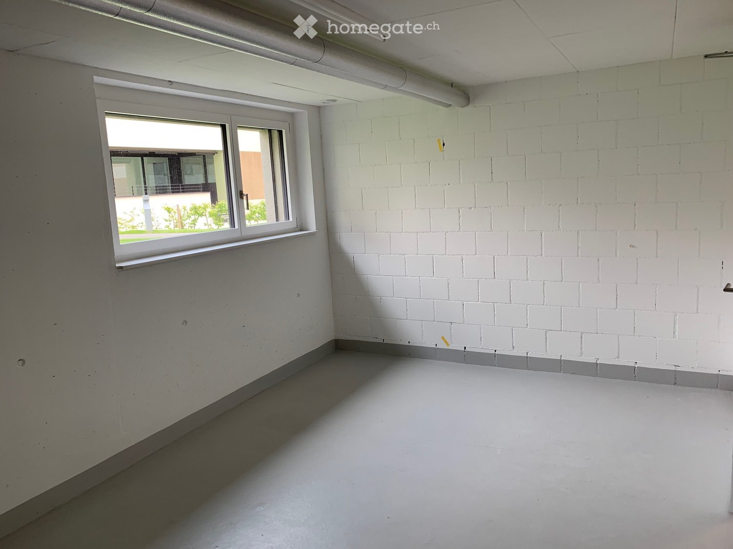 Empty room with white walls, a window, and concrete floor